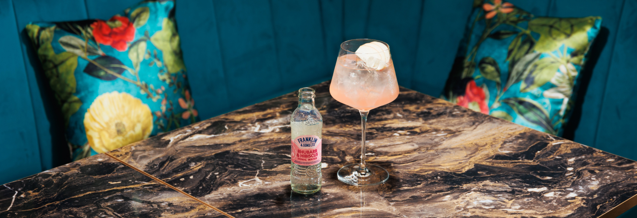 Rhubarb and hibiscus toni water next to a spritz cocktail with a slice of apple as the garnish | Franklin & Sons