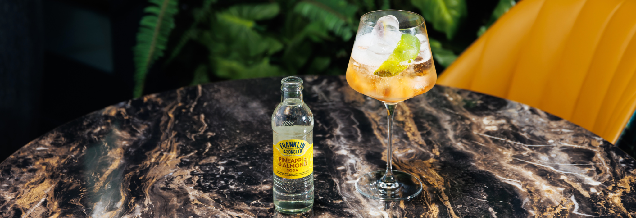 Pineapple and almond soda next to a spritz cocktail with a lime peel as the garnish | Franklin & Sons